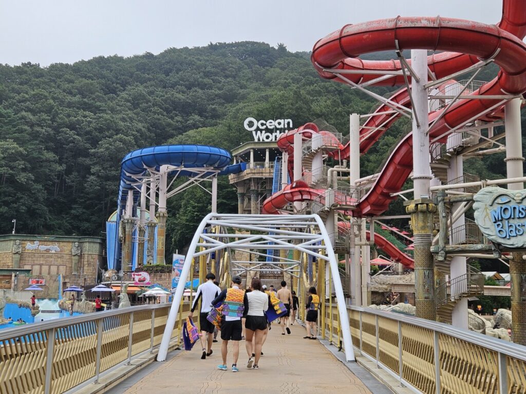 Visitors walking across bridge toward Monster Blaster and water slides at Ocean World Korea