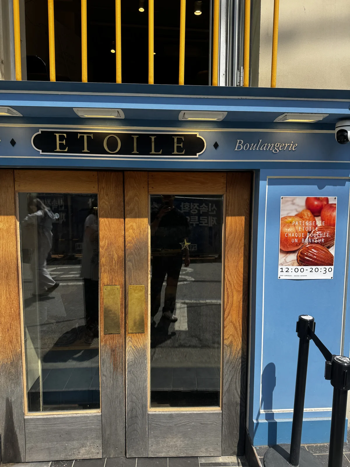 Blue storefront of Etoile Garosugil boulangerie with its opening hours poster
