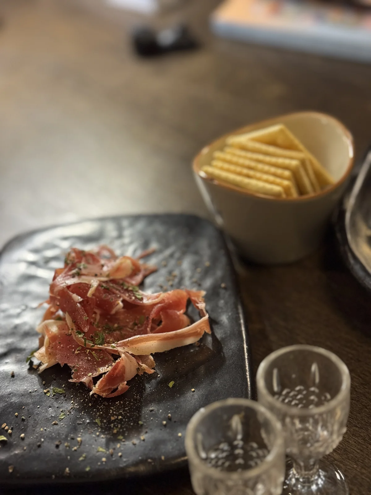Thin jamon slices and crackers pair well with whisky flights at Jeokon