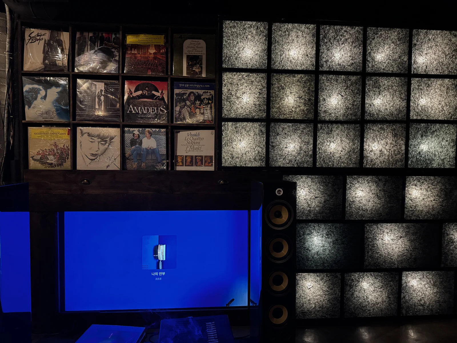 Vinyl records and a glowing paper light wall beside Focal speakers at Jeokon